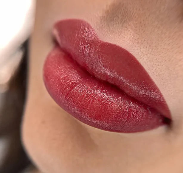 Close-up of a person's lips wearing a glossy red lipstick.
