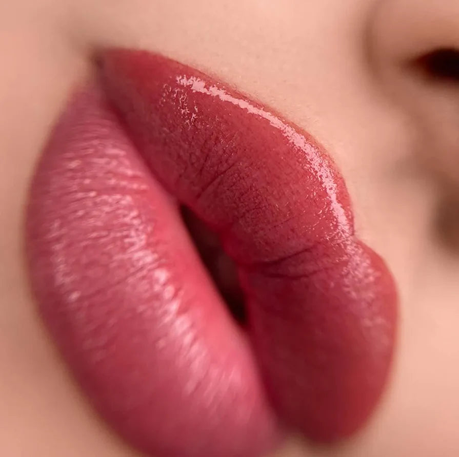 Close-up of glossy red lipstick on lips with a blurred background